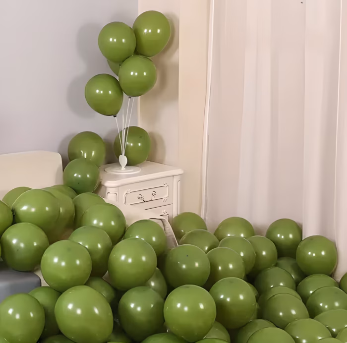 Set 100 Baloane Latex Olive Green Retro (30 cm) | Decor Kaki Premium O multime de baloane din latex de 30 cm, complet umflate cu aer, in nuanta pamantie olive green retro sau kaki. O parte din baloane sunt asezate pe un suport alb de masa cu bete, creand un buchet elegant pe o noptiera, in timp ce zeci de alte baloane asortate sunt imprastiate bogat pe podea si pe marginea patului.